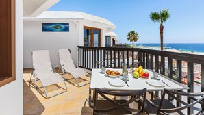 Un balcon avec une table préparée pour le petit-déjeuner, donnant sur une plage et la mer.