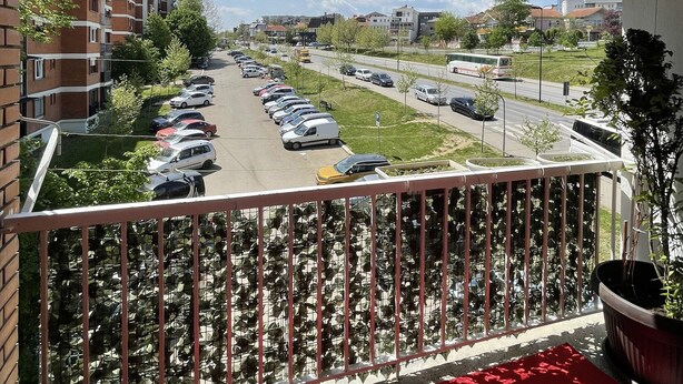 A balcony with a view of a parking lot and buildings. - SunnyHill Apartments (Pristina)