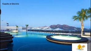 En swimmingpool med utsikt över berg och palmer.
