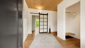 Un couloir avec une porte coulissante, un plancher en bois, un tapis gris et un portant suspendu.
