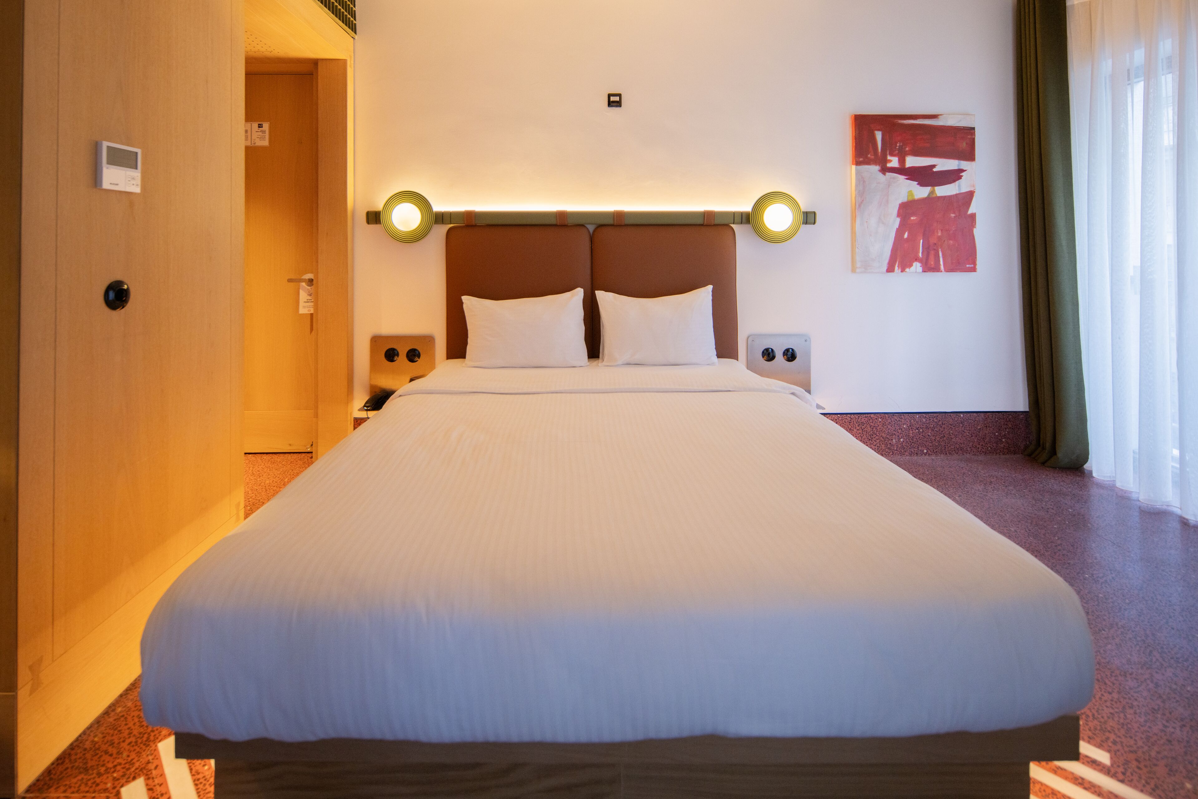 A large bed with a wooden headboard, bedside tables, and a wall-mounted light fixture.