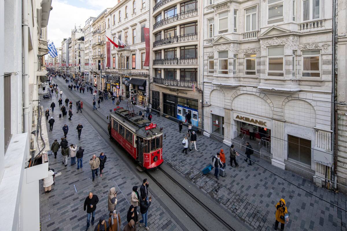 A busy urban street with a tram, pedestrians, and historic buildings.
