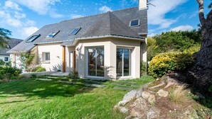 A two-story house with a sloped roof, large windows, and a well-maintained lawn. - Villa with heated pool & garden - 5 min from the sea, by Groom (Guidel)