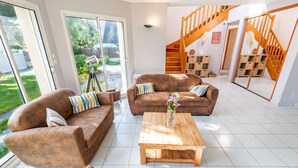 A spacious living area with two brown sofas, a wooden coffee table, and a staircase with wooden railings. - Villa with heated pool & garden - 5 min from the sea, by Groom (Guidel)