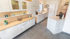 Une cuisine moderne avec des meubles de couleur bois clair, un îlot central et un bar pour prendre le petit-déjeuner.