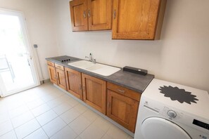 Una cocina con armarios de madera, un lavabo, una estufa y una lavadora.