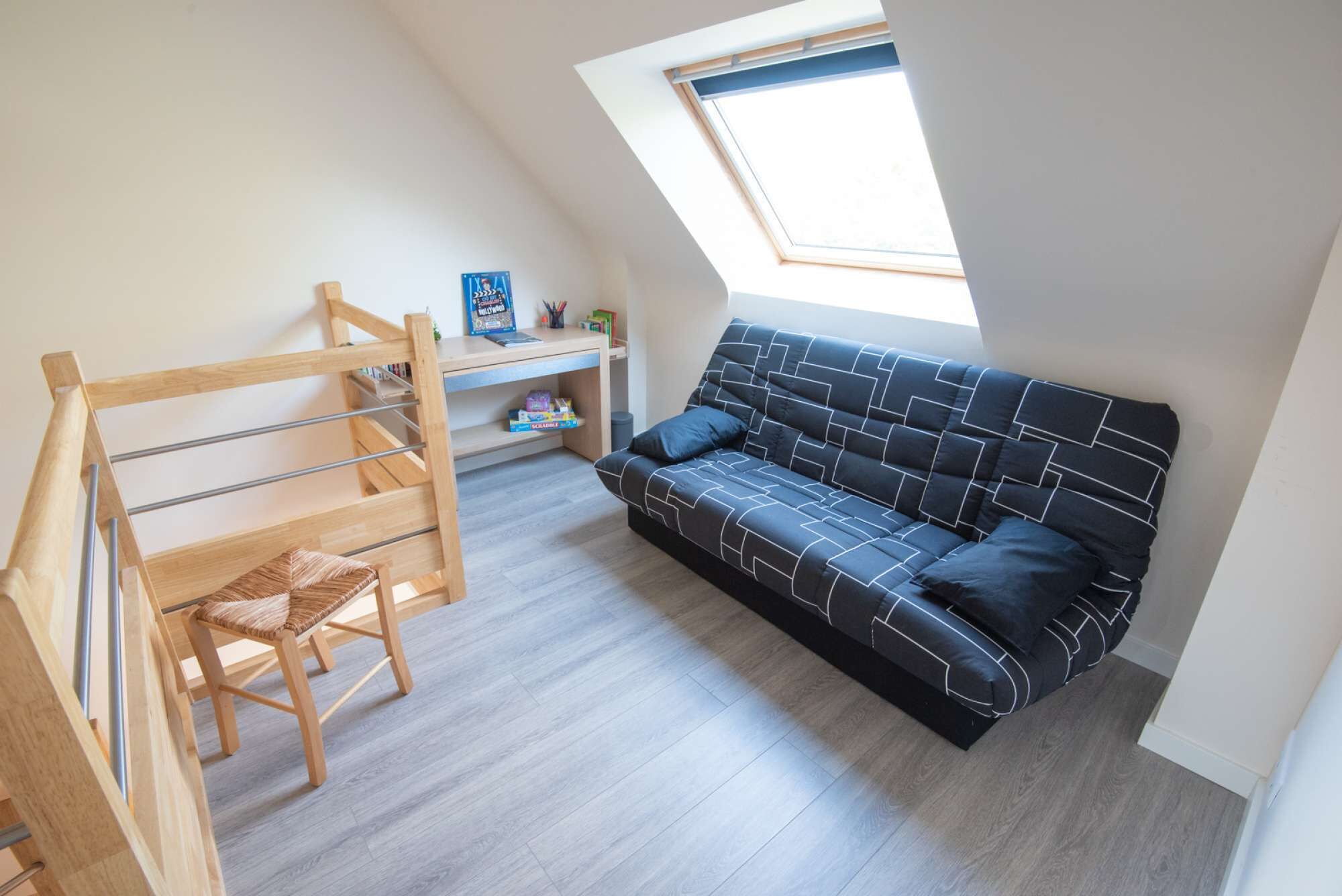 Ein Zimmer mit Etagenbett, einer Schlafcouch, einem Schreibtisch und einem Dachfenster.