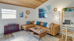 Ein modernes Wohnzimmer mit Holzboden, einem braunen Ledersofa, einem Couchtisch aus Holz und einem Bücherregal mit Dekoration.