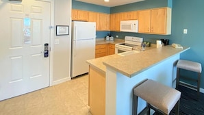 Una cocina moderna con armarios de madera, microondas integrado y una isla central con taburetes de bar.
