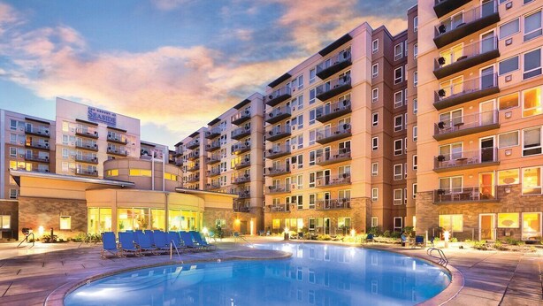 Un hotel con varias plantas, piscina y zonas de estar al aire libre.