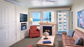 Una sala de estar con chimenea, televisión y vista a la playa.