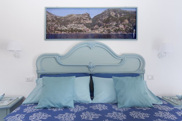 A bedroom with a bed, two bedside tables, a wall-mounted picture, and a nightstand.