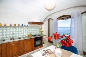 Enjoy a home-cooked meal in this kitchen with a gas stove, oven, and sink, offering a view of the sea through the window.