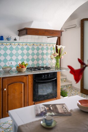 Kitchen area with gas stove, oven, and sink, featuring a decorative backsplash and dining space.