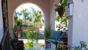 Un patio exterior con un banco, plantas en macetas y suelo de baldosas.
