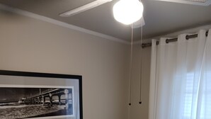 Un dormitorio con cama, un cuadro enmarcado en la pared y una ventana con cortinas.