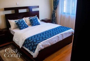 Relax in this inviting bedroom with a comfortable bed, adorned with pillows and a bed runner, and a convenient nightstand with a lamp.