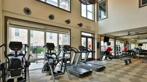 Une salle de sport équipée de tapis de course, de vélos elliptiques et de poids.