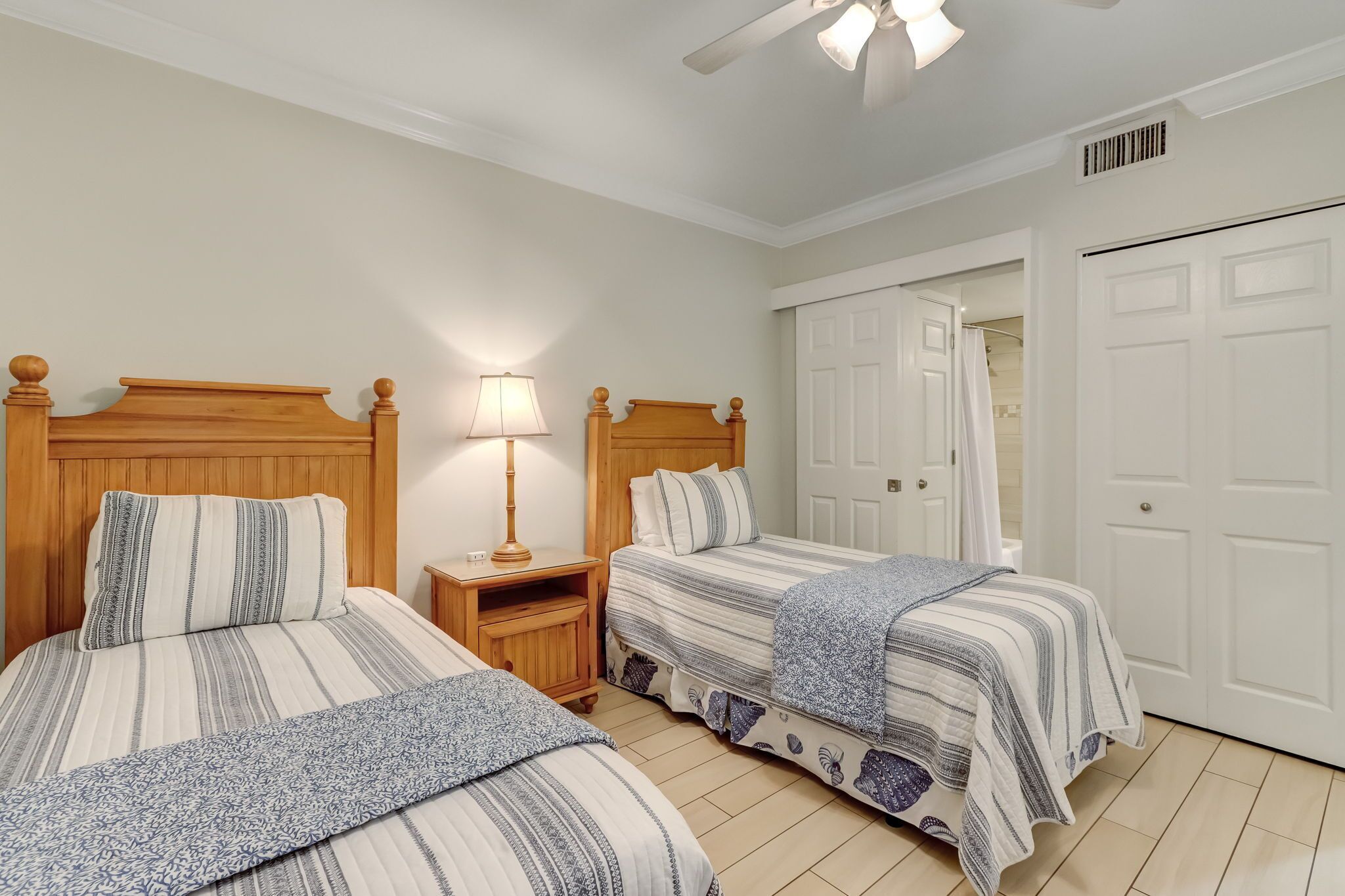 Une chambre d’hôtel avec deux lits, des têtes de lit en bois, une table de chevet avec une lampe et une armoire.