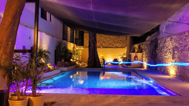 An indoor swimming pool with a stone wall and a ceiling that appears to be part of a larger building structure. - ACQUA IN BOCCA (Mérida)