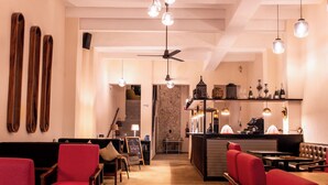 A restaurant with red upholstered chairs, a bar area, and a ceiling fan. - ACQUA IN BOCCA (Mérida)