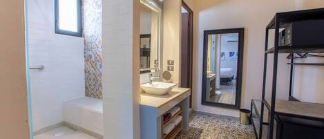 A modern bathroom with a bathtub, a sink with a mirror, and a shower area.