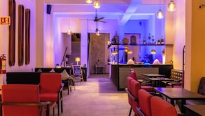 A restaurant with red chairs, a bar area, and a staircase leading to an upper level. - ACQUA IN BOCCA (Mérida)