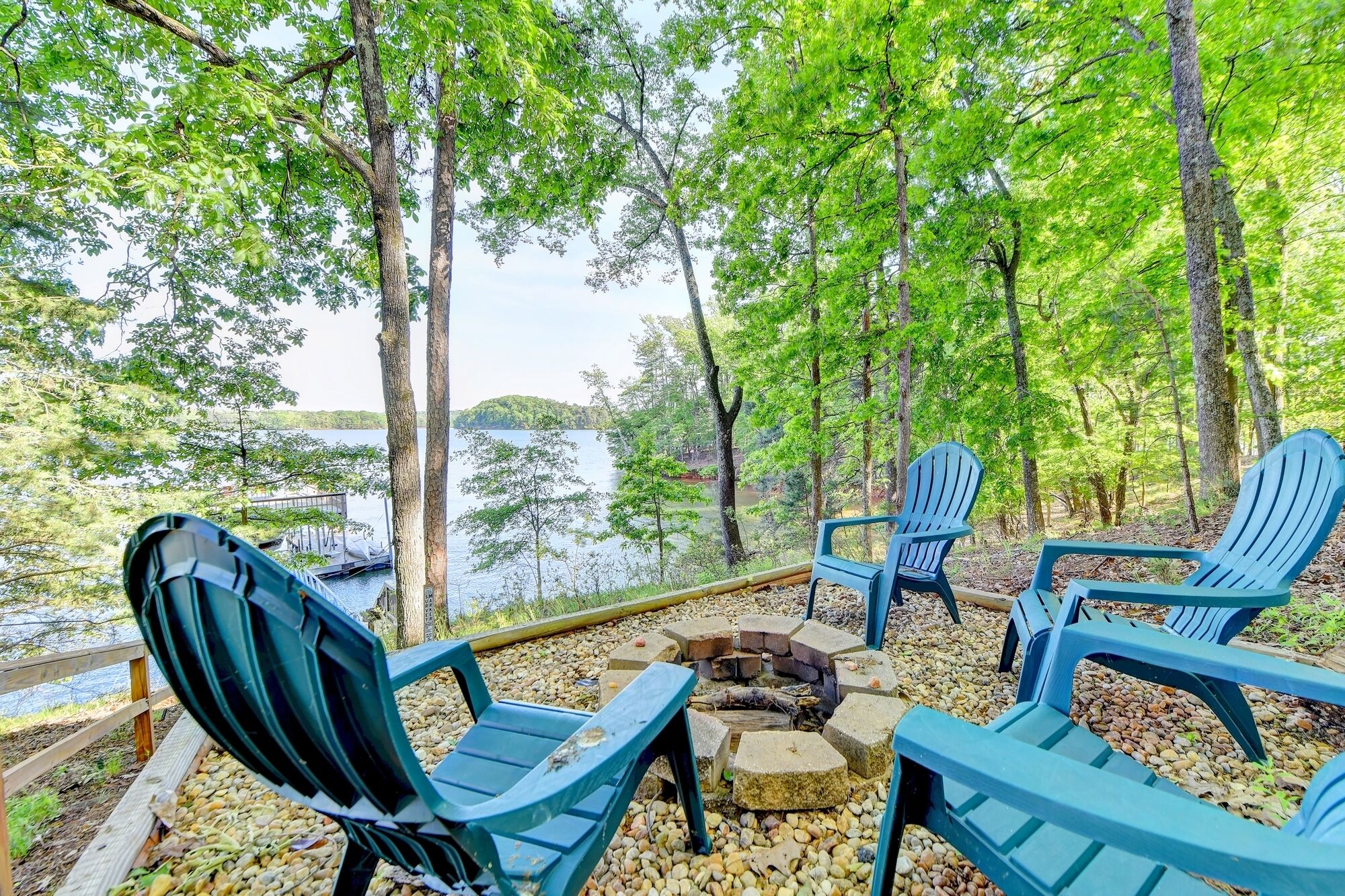 A lakeside seating area with Adirondack chairs and a fire pit.