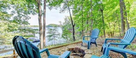 A lakeside seating area with Adirondack chairs and a fire pit.