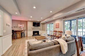 A spacious living room with a fireplace, a television, and a balcony with a view.