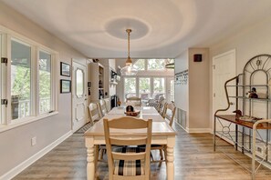A dining area with a long table, chairs, and a hanging light fixture.