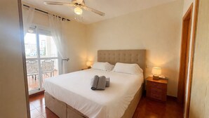 A bedroom with a bed, a ceiling fan, a nightstand, and a view of the outside. - AP376 VALPARAISO (Nerja)