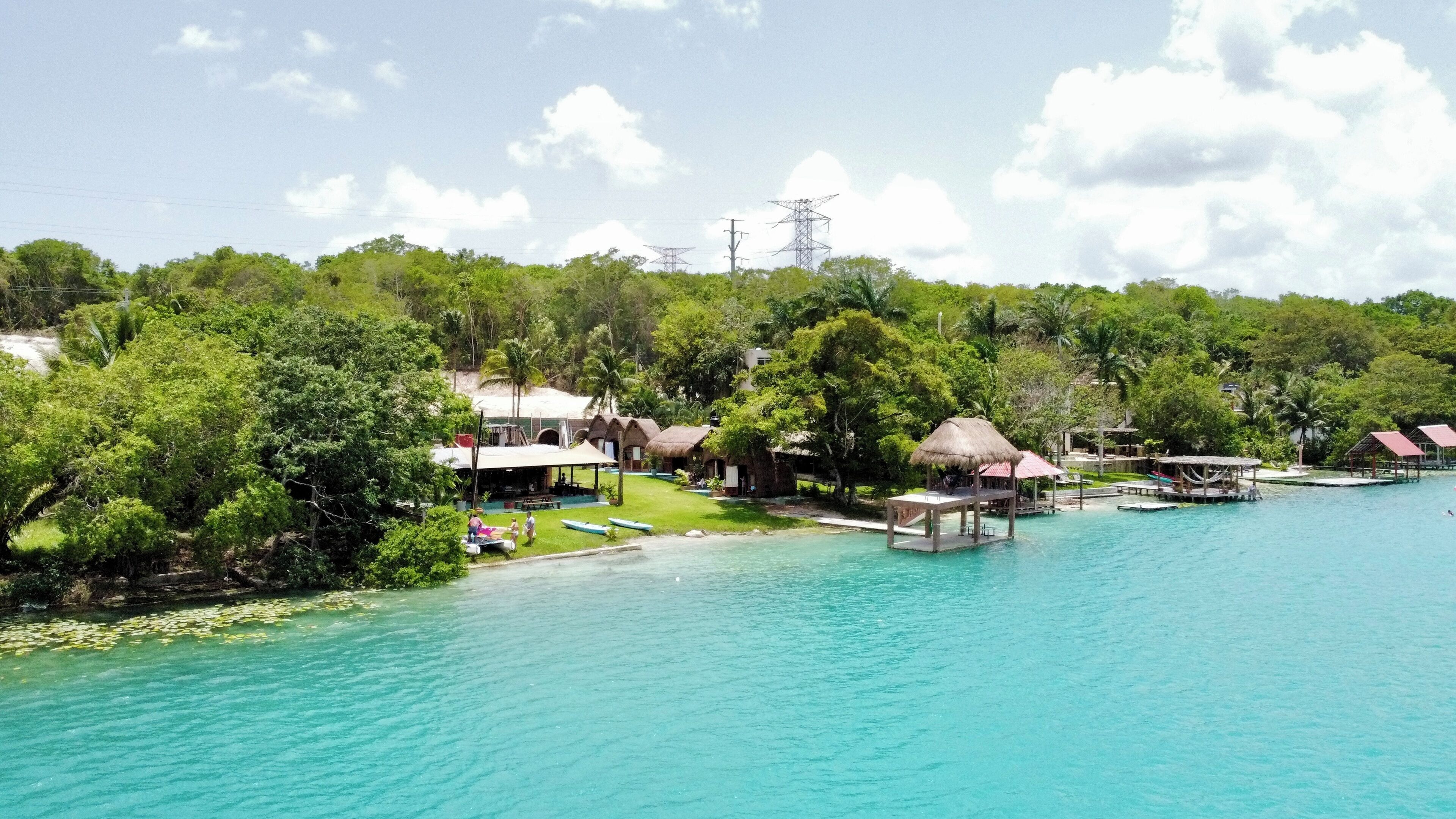 Un resort tropical con cabañas de techo de paja, una piscina y abundante vegetación.