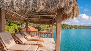 A beachside lounge with wooden loungers and a thatched roof, overlooking a calm sea and lush greenery. - Pepos Xul-Ha (Xul-Ha)
