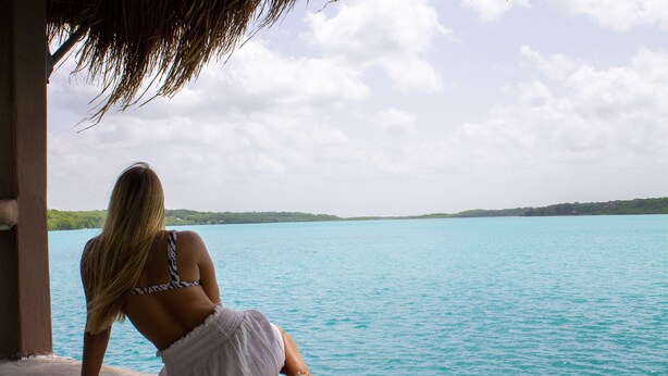A person sitting by a body of water, overlooking a distant shoreline. - Pepos Xul-Ha (Xul-Ha)