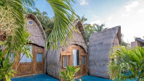 A thatched-roof building with wooden doors and windows, a blue pool, and surrounding palm trees. - Pepos Xul-Ha (Xul-Ha)