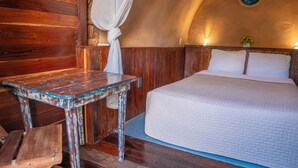 A rustic room with a wooden bed, a small table, and a hanging light fixture. - Pepos Xul-Ha (Xul-Ha)