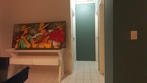 A hallway with a tiled floor, a bench, and a colorful painting on the wall. - Apartamento da Cor do Mar - VR-1202 (Recife)