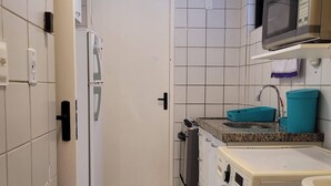A compact kitchen with a microwave, a washing machine, and a sink. - Apartamento da Cor do Mar - VR-1202 (Recife)