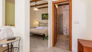 A bedroom with a bed, a bedside table, a hanging light fixture, and a painting on the wall. - CASA SAINA - Studio Limone (Rovinj)