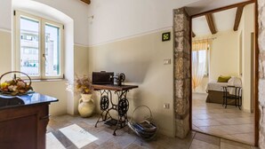 A room with a sewing machine on a table, a window with a view, and a bed with a green pillow. - CASA SAINA - Fiordaliso (Rovinj)
