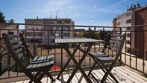 A balcony with a table and two chairs, overlooking a residential area with buildings and a clear sky. - CASA SAINA - Fiordaliso (Rovinj)