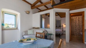 A cozy room with a bed, a table with a bowl, a chair, a window, and a door leading to another room. - CASA SAINA - Fiordaliso (Rovinj)