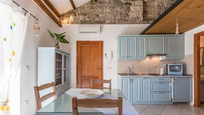 Una cocina acogedora con armarios azul claro, una mesa de madera con sillas y una pared de piedra sobre la cocina.