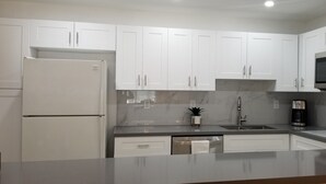 A modern kitchen with white cabinets, a built-in microwave, a coffee maker, and a sink. - 
Miami CONDO Family-Friendly Beach Condo w/ Full Kitchen, Aventura Mall (Sunny Isles)