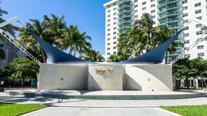 A modern hotel with a prominent entrance featuring a unique architectural design with a curved roof structure. - 
Miami CONDO Family-Friendly Beach Condo w/ Full Kitchen, Aventura Mall (Sunny Isles)