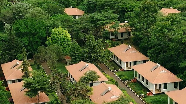 A residential area with multiple houses, each with a sloped roof and surrounded by greenery. - Ngorongoro Corridor Lodge (Karatu)