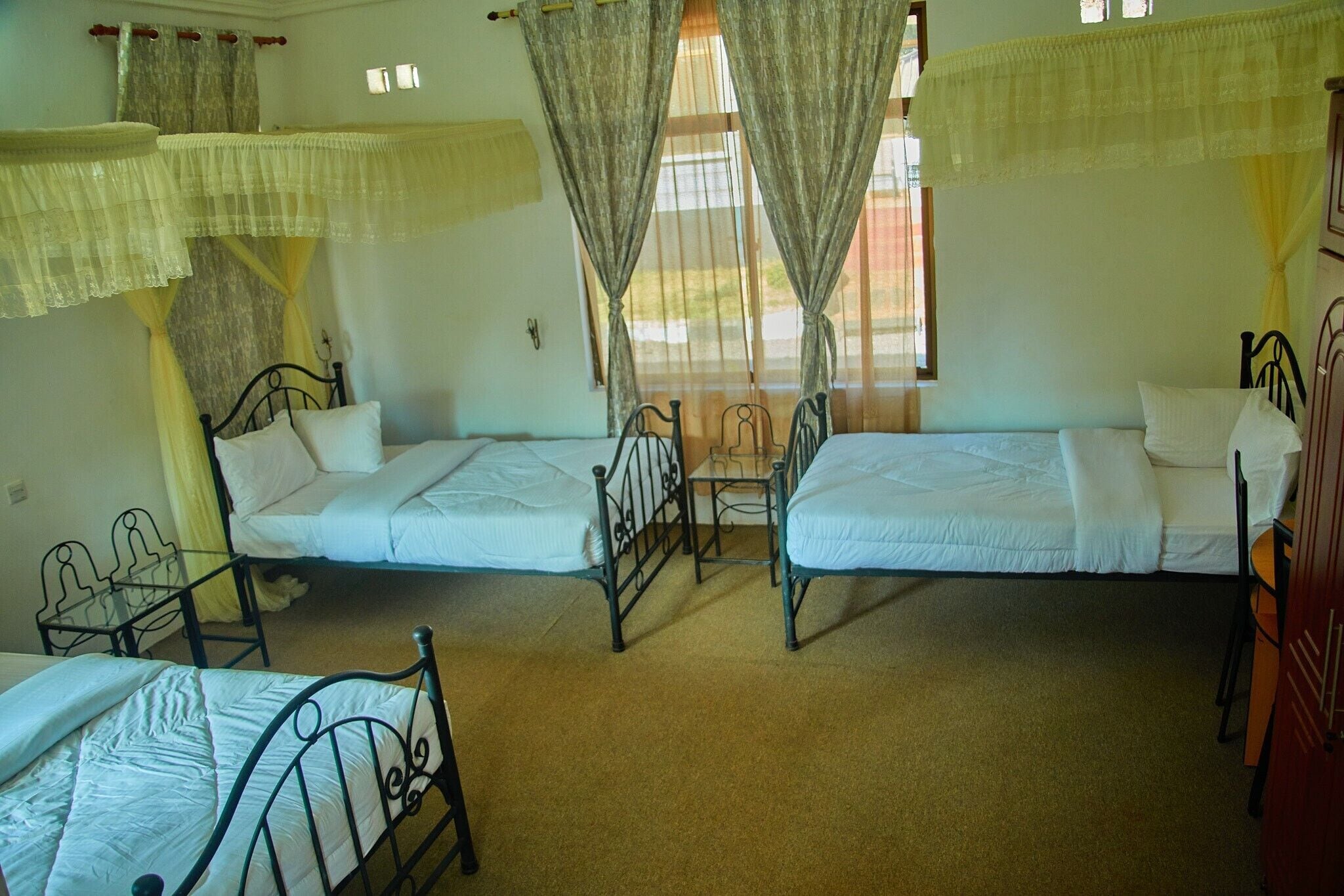 A room with two single beds, a small table, and a chair.