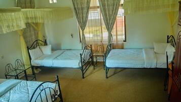 A room with two single beds, a small table, and a chair.