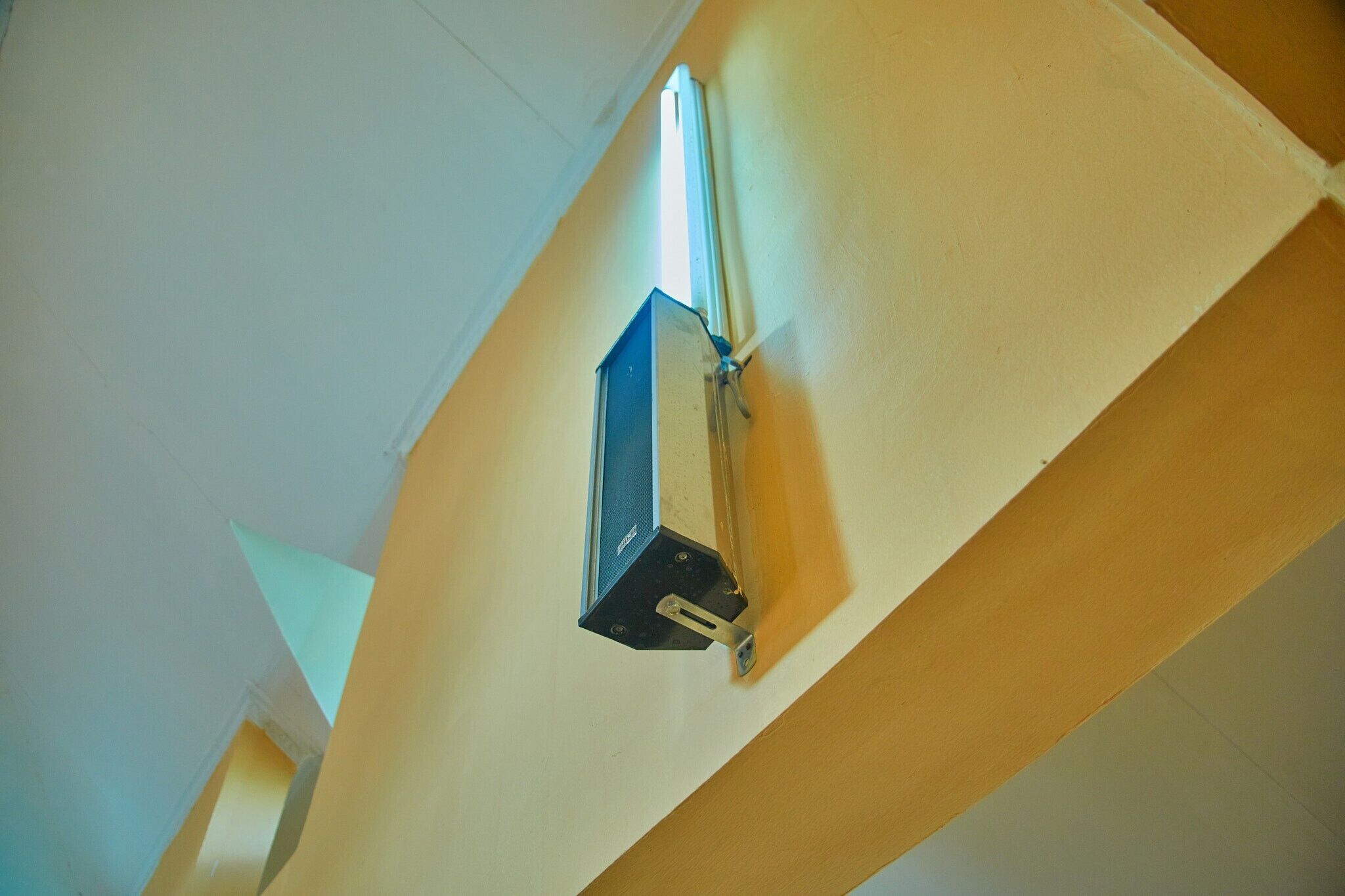 Rincón de una habitación con una lámpara de techo y una viga de madera.